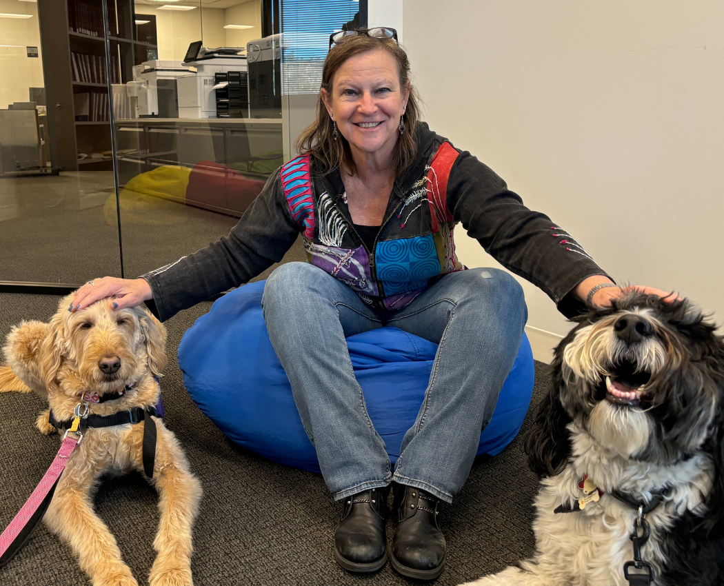Woman in an office petting two therapy dogs.